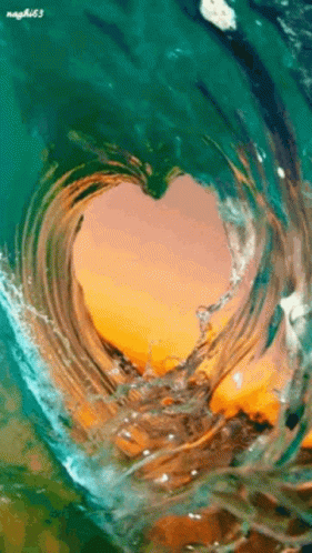 a heart shaped wave with water and a blue sky