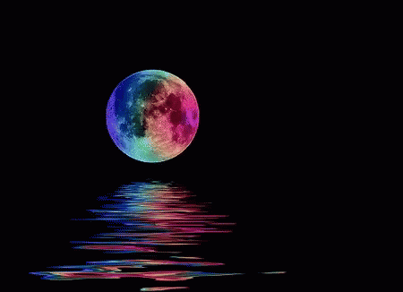 a colorful full moon rising over the water on a black night