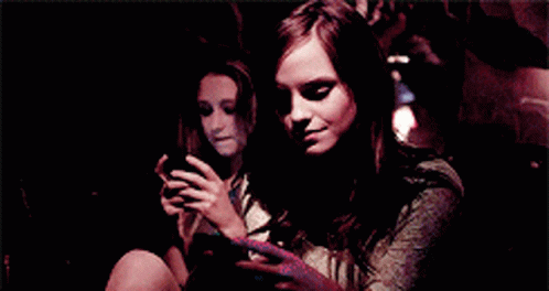 two girls with dark hair are looking at their cell phones