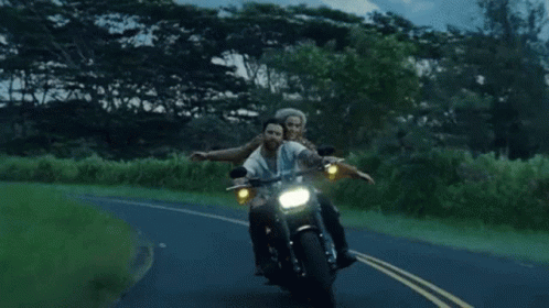two people riding on the back of a motorcycle