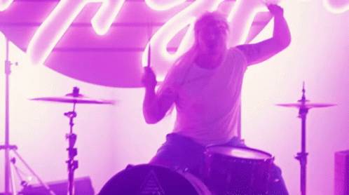 a drummer in shorts holds his drums up