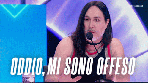 a woman in black shirt at microphone with word that says oddio mi sono offeso