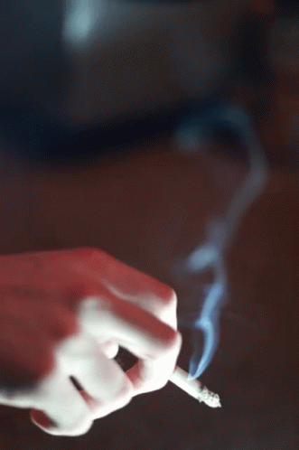 a hand with a blue glove holding out a lit cigarette