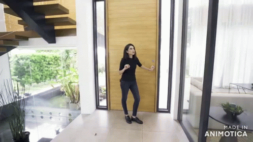 the woman is entering the house with a hand gesture