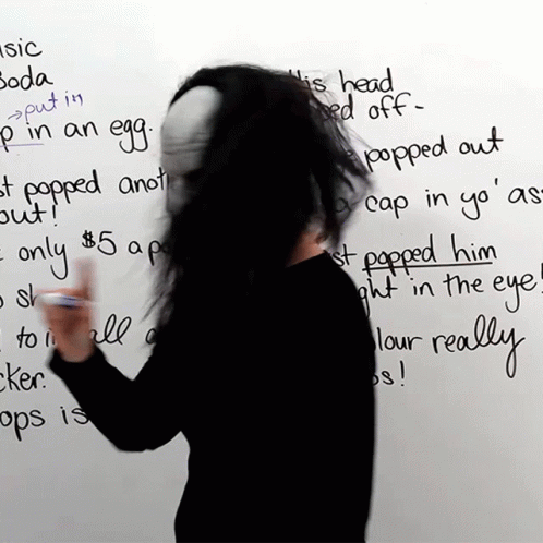 a person holding a cup in front of a writing on a wall