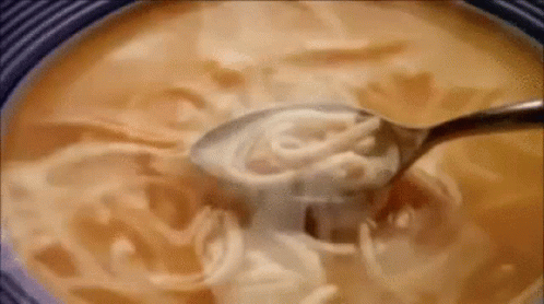 a spoon filled with soup that has soing cream on it