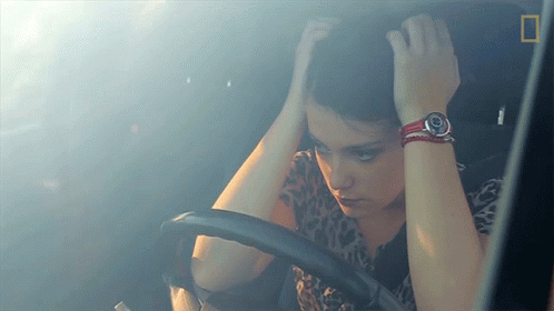 a woman with her hands over her head while driving
