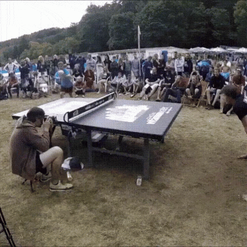 a game of ping pong is being played in a crowded area