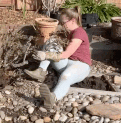 a little girl is sitting on some rocks and gardening
