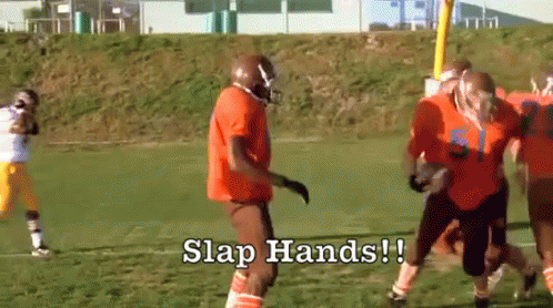 three football players on field with handwritten slap hands
