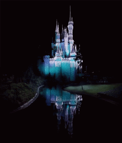 the castle at night, lit up, is reflected in the water