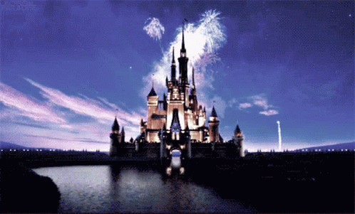 disney castle with fireworks lit in the sky and people on the sidewalk