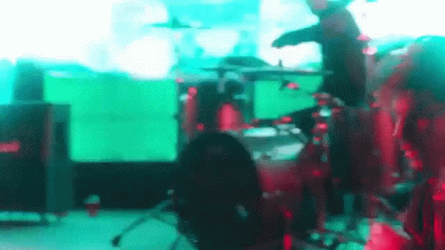 two men are playing drums in front of video screens