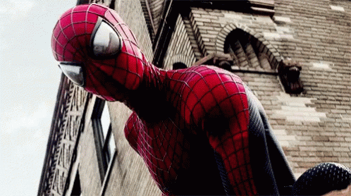 a spider man sculpture is standing next to a large brick building