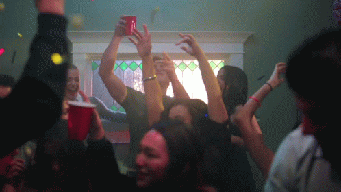 people at a party are raising their hands up