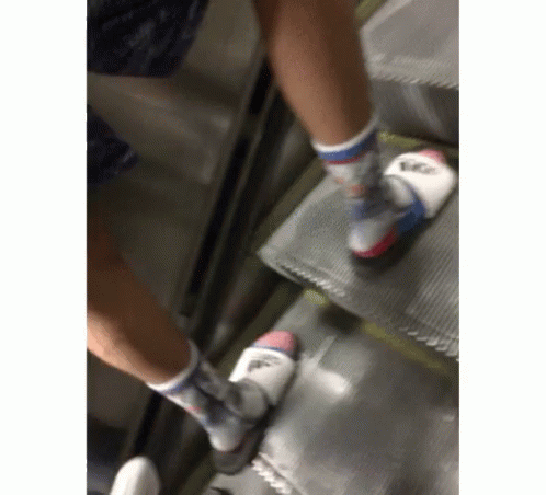 two persons in sports shoes moving along an escalator