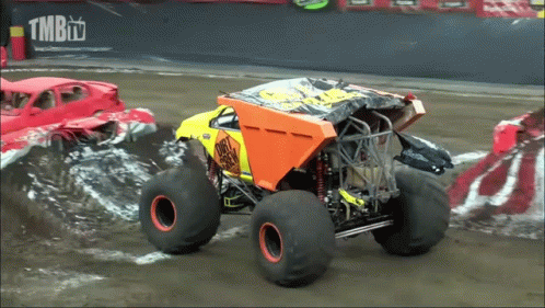 two monster trucks with large wheels going through the water