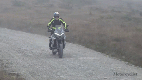 a man riding a motorcycle on top of a dirt road