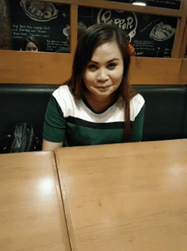 a girl looking up at the camera while sitting at a table