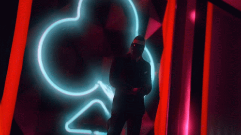 a person stands under a neon heart sign