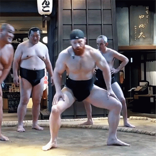 a bunch of sumo wrestlers stand near each other