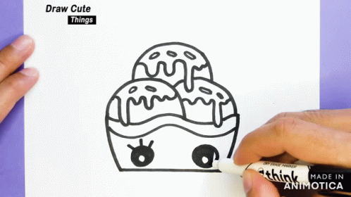 a person holds a marker near an envelope with a drawing of a cupcake