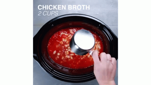 someone putting some chicken broth in a pot