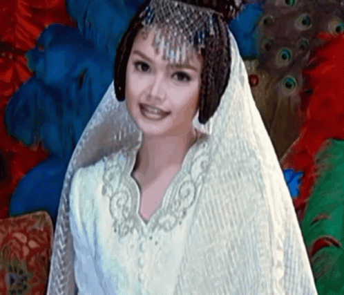 a woman wearing a white dress and veil in a peacock room