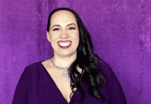 a woman with purple makeup smiling for the camera