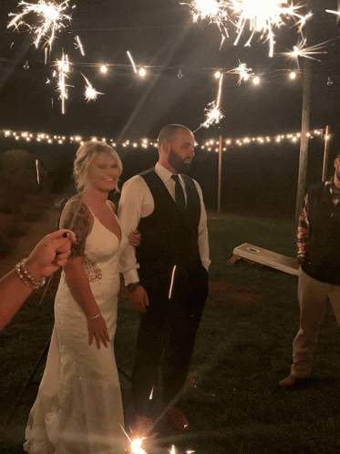 a bride and groom walking with sparklers around them