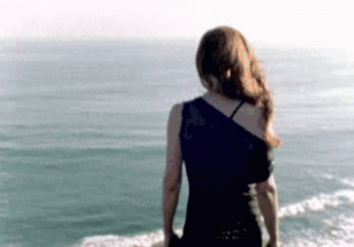 a girl walking along the beach with her dress open