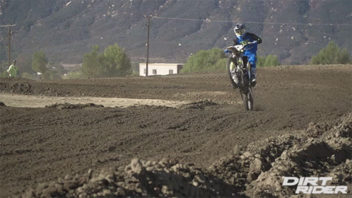 two men ride motorcycles in the mud by a mountain