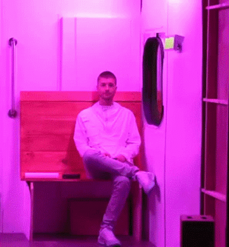 a person sitting in a doorway next to a purple wall