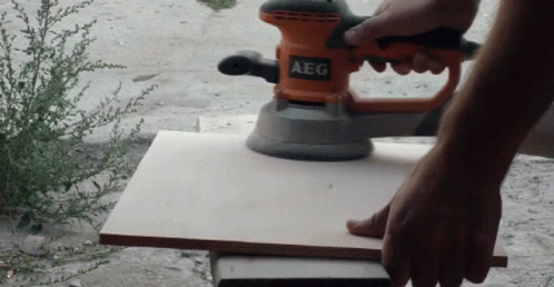 a person with a sandblader is sanding the top of the table