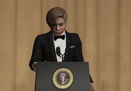 a man in a tuxedo standing behind a podium talking