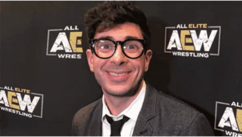 a man with glasses and a suit in front of an all aew background