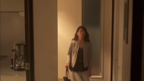 a woman walking through a hallway with a purse