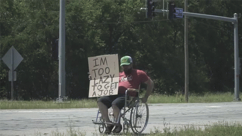 man in a wheelchair being led by another man through a road