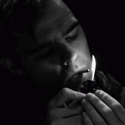 black and white pograph of man with a lit candle in his mouth