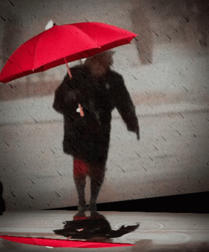 a person with a blue umbrella walking on a runway
