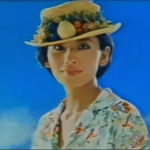 a woman wearing a sun hat standing in front of a yellow wall