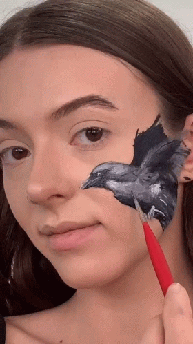 a woman looking at a drawing of a bird on her face