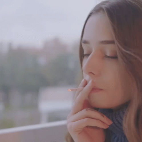 a woman smokes an cigarette while outside on a street