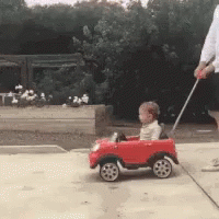 an old man hing a toddler car in a driveway