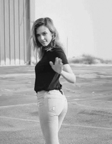 a woman posing in a parking lot in front of a building