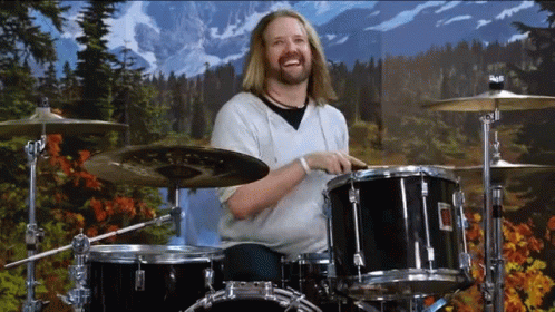 a man playing drums in front of a mountain backdrop