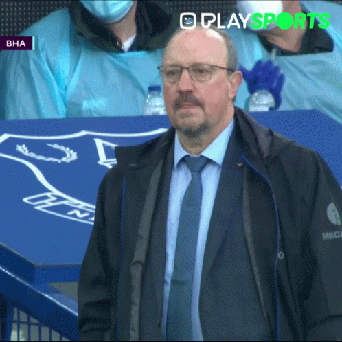 a man in glasses is standing next to a soccer bench