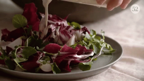 someone is pouring water on a plate with purple and green flowers