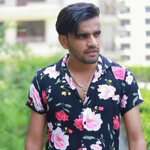man standing outside in colorful shirt with flowers on it
