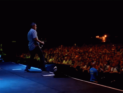 a man is walking towards the stage with a guitar